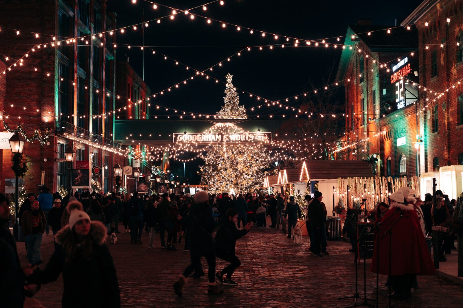 Crowd enjoying a festive Christmas market at night under twinkling lights